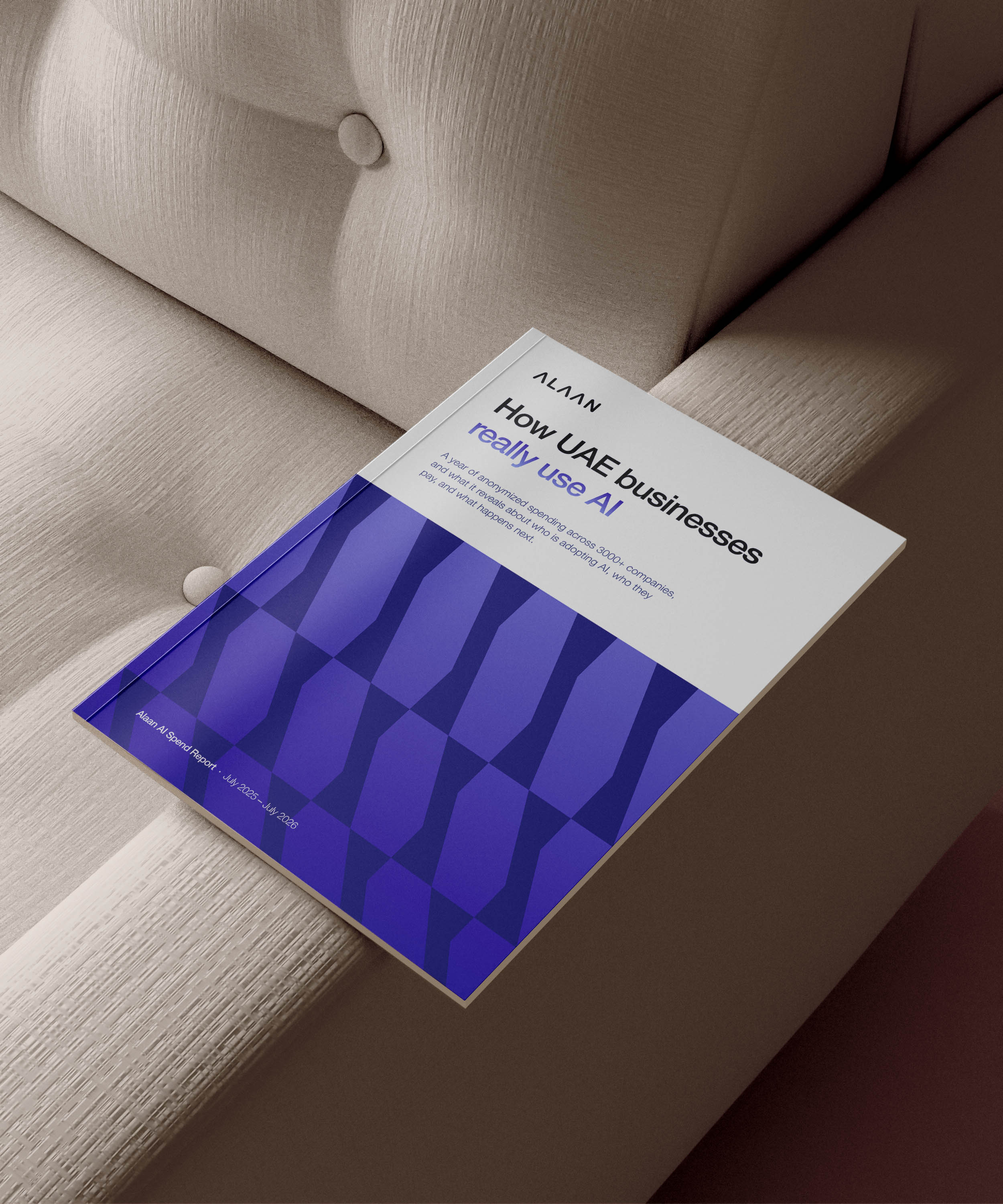 Report titled 'How UAE businesses really use AI' by Alaan, placed on a beige tufted couch. The report cover features a geometric blue pattern and mentions a year of anonymized spending across 3000+ companies, revealing who is adopting AI, how they pay, and what happens next, dated July 2025 to July 2026.