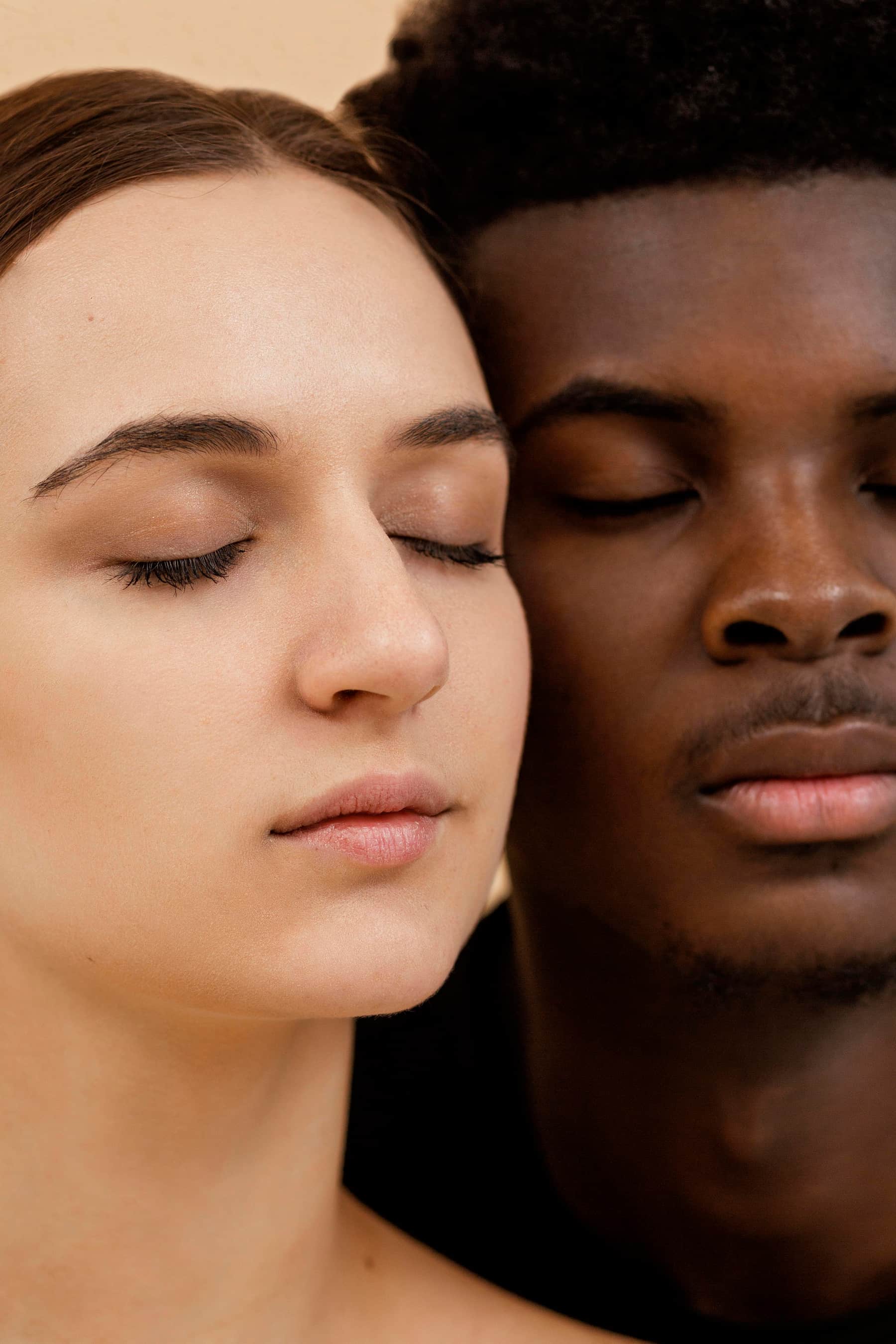 Portrait en gros plan d'un couple interracial avec les yeux fermés, exprimant paix et sérénité.