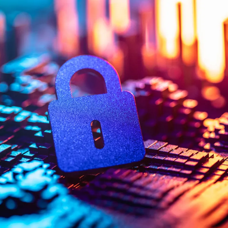 Blue padlock symbol on a computer chip background with colorful lighting representing cybersecurity.
