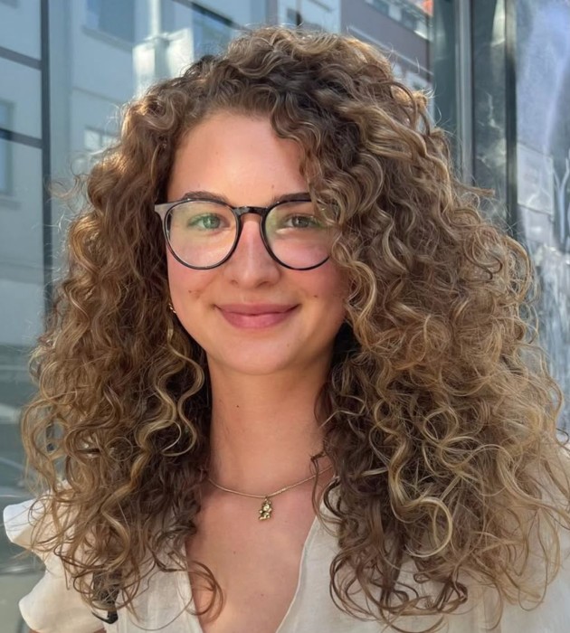Frau mit langen, lockigen Haaren und Brille
