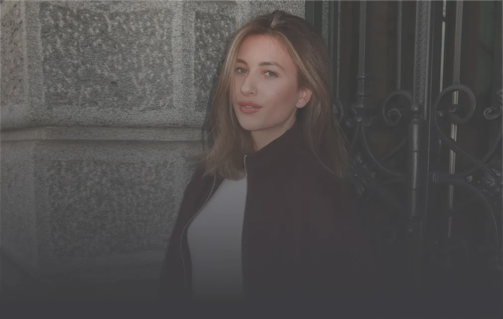 Man with blonde hair and tattoos sitting inside a boxing ring with red and blue ropes.