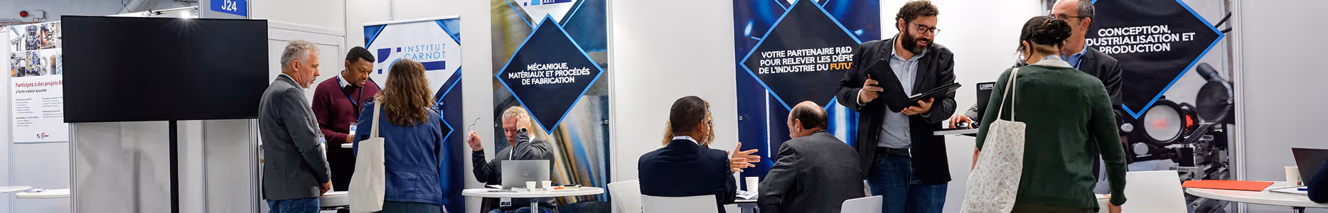 Personnes discutant et travaillant dans un stand d'exposition avec des panneaux de l'Institut Carnot.