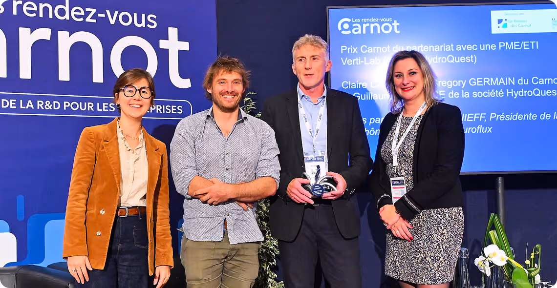Quatre personnes souriantes posant lors d'une remise de prix Carnot avec un trophée.
