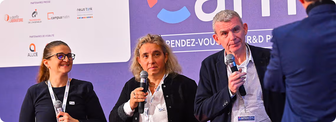 Trois personnes tiennent des micros lors d'un événement avec un fond violet affichant des logos et du texte.