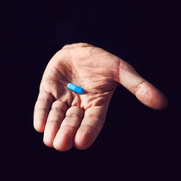 Hand on black background that shows a blue pill like in the Matrix movie