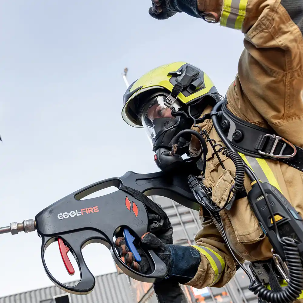 Close-up van een brandweerman met Coolfire-lans in actie. De ergonomische vorm en dubbele triggers tonen de slimme, intuïtieve bediening waarmee rookgassen snel en gecontroleerd bestreden kunnen worden – van buiten het brandcompartiment.