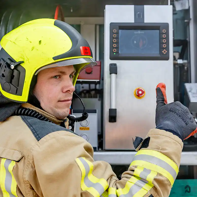 Brandweerman verlaat een brandend compartiment tijdens een oefening. De vlammen illustreren de intensiteit van een binnenbrand en benadrukken het belang van de Coolfire-methode: veilig koelen van buitenaf, zonder directe blootstelling aan hitte of rookgassen.