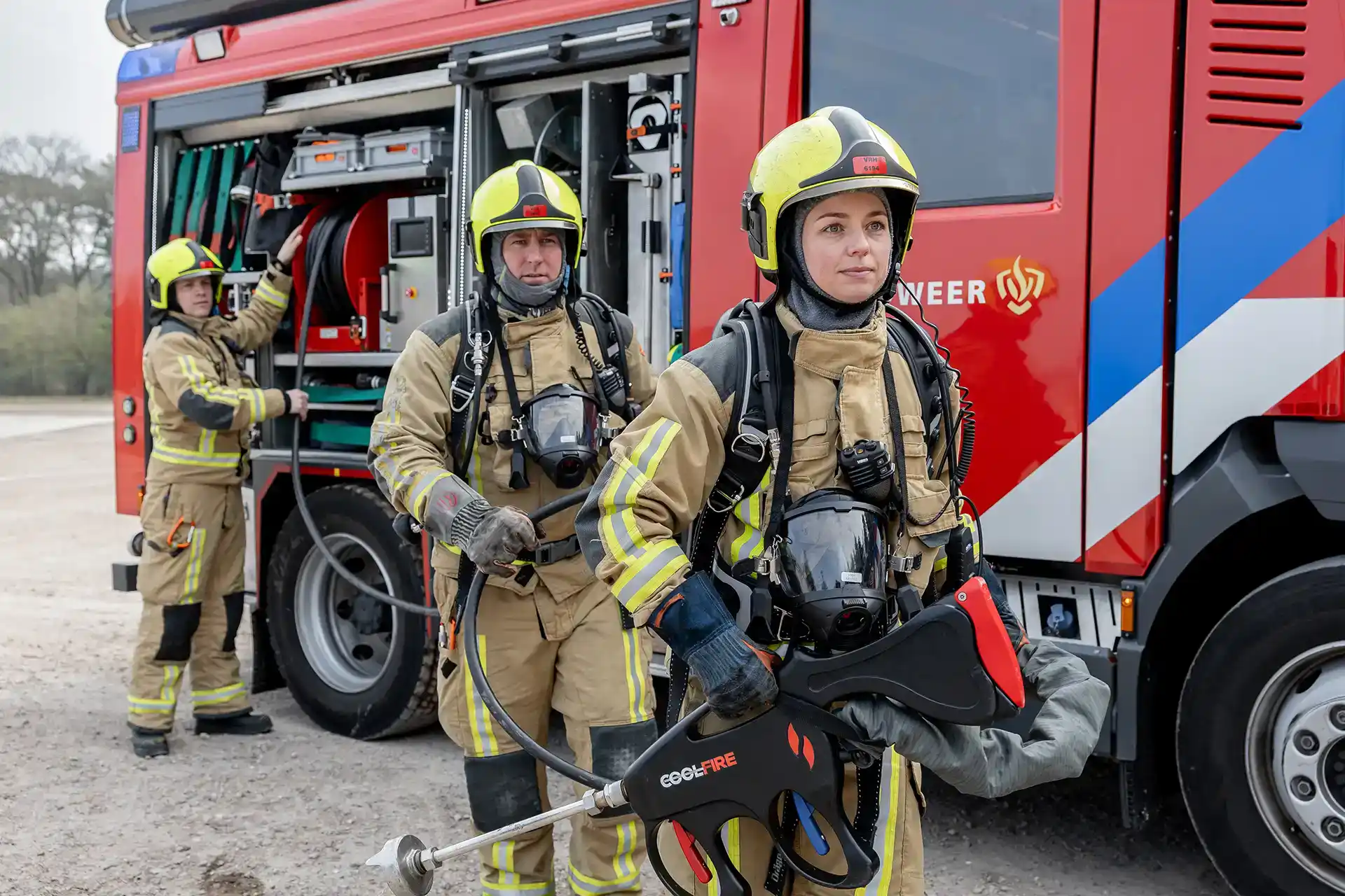 Brandweerteam met complete Coolfire-uitrusting bij het blusvoertuig. De ergonomische lans, hogedrukslang en slanghaspel tonen het modulaire systeem waarmee branden sneller, veiliger en efficiënter bestreden worden.