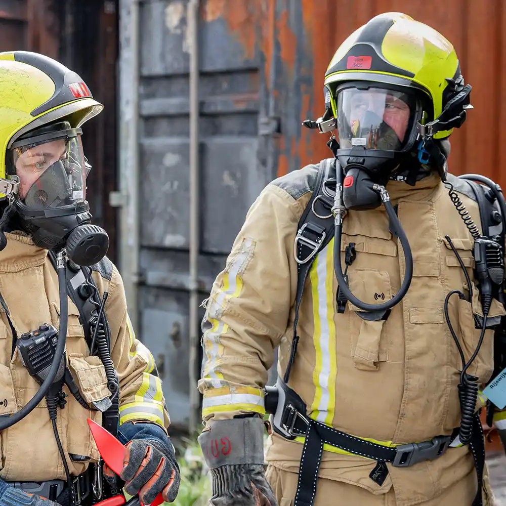 Twee brandweerinstructeurs in volledige ademluchtuitrusting tijdens een Coolfire-training. De setting toont de professionele voorbereiding en kennisoverdracht die centraal staan in de instructeurstrainingen van de Coolfire Academy.