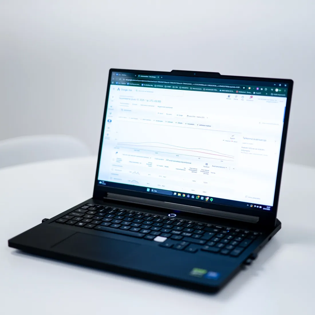 Kädellä pidellään älypuhelinta, jonka näytöllä näkyy Google Analytics -raportin kaltainen kaavio tai dataa. Taustalla on sumea kaupunkimaisema.