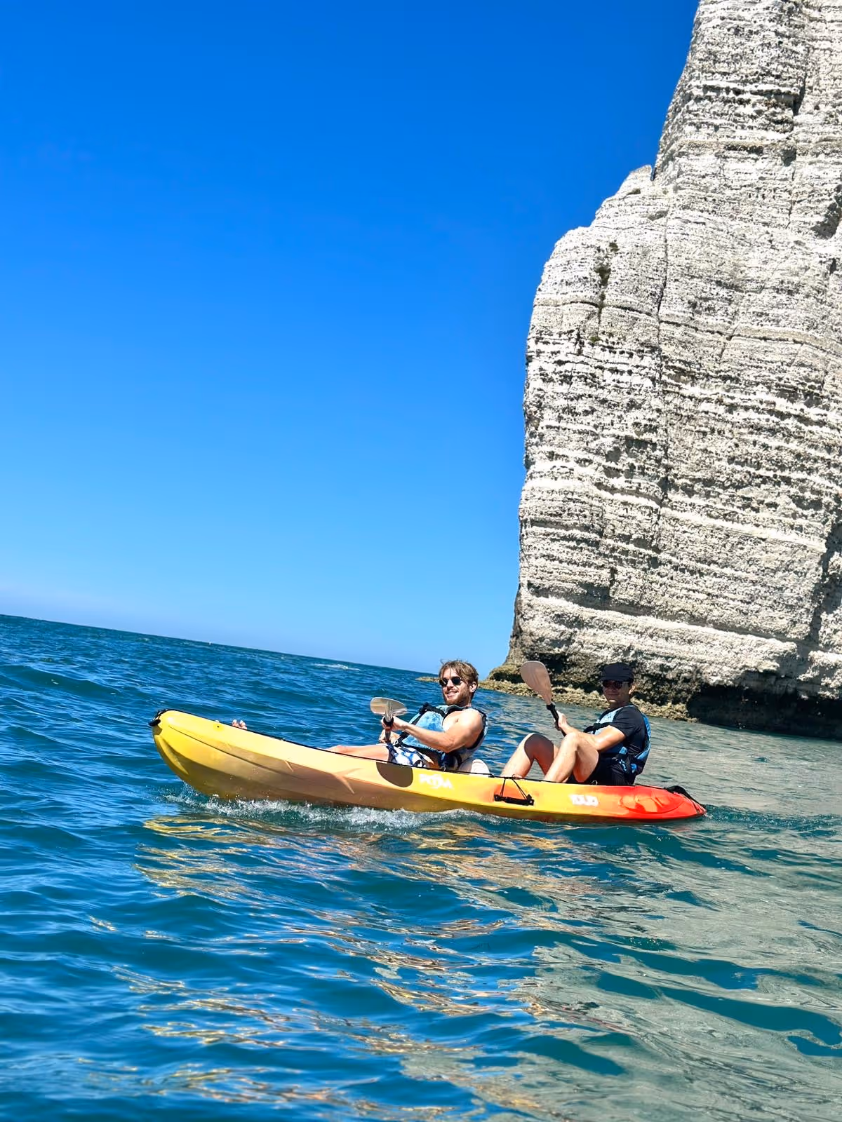 Flowlity team members kayaking near sea cliffs during team building