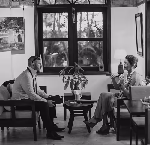 photo en noir en blanc d'un homme et d'une femme assis face à face dans un lieu cosy qui discutent