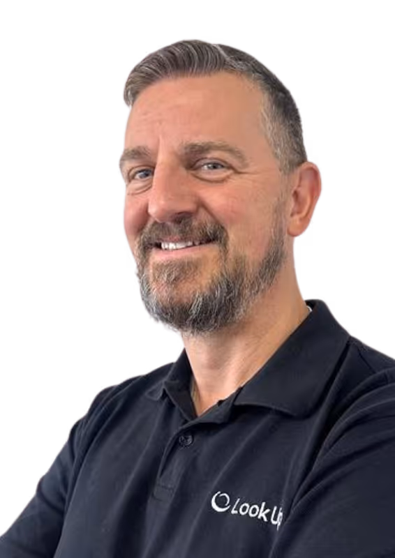 Smiling man with short gray hair and beard wearing a black polo shirt with the Look Up logo.