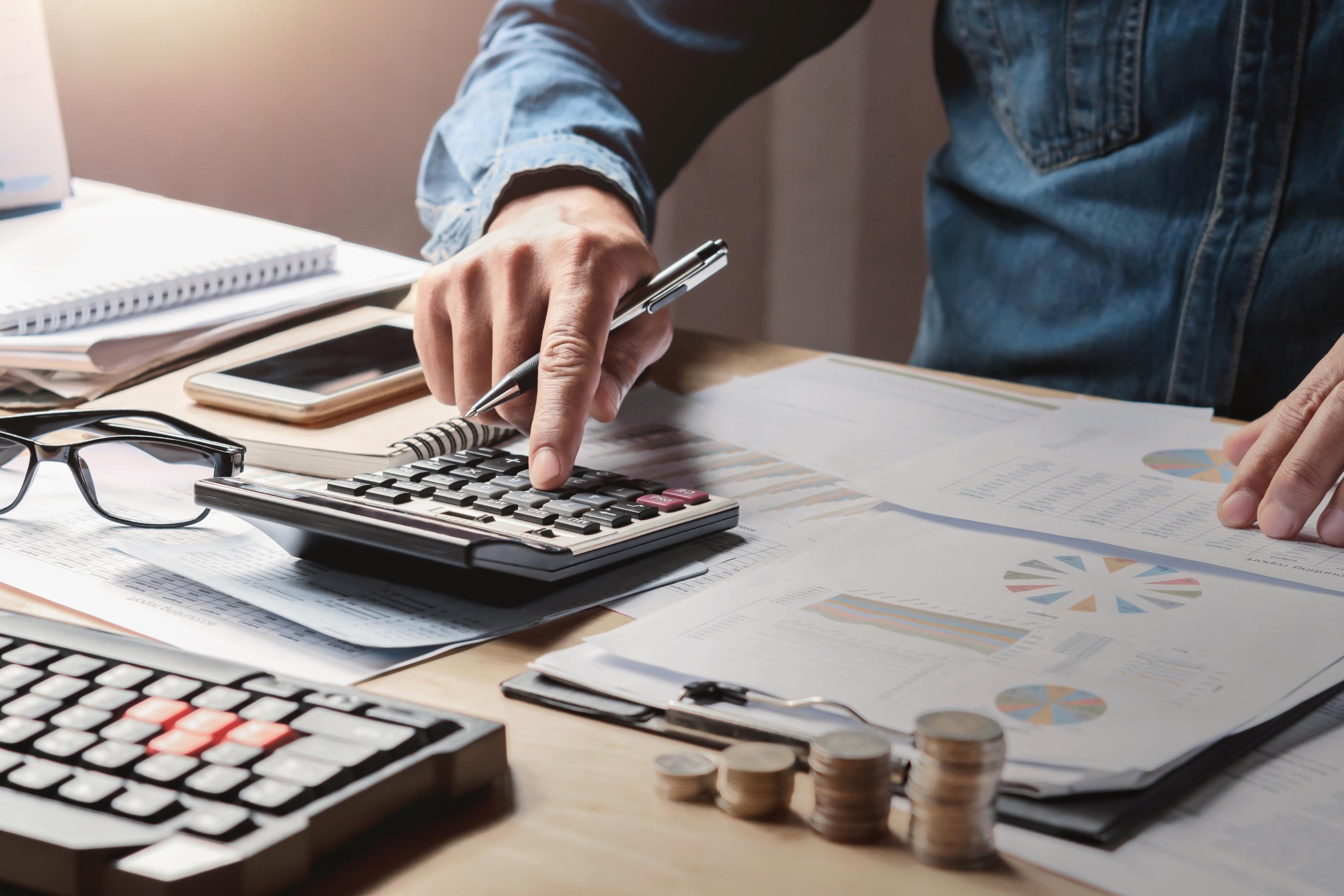 Financial professional analyzing reports with a calculator