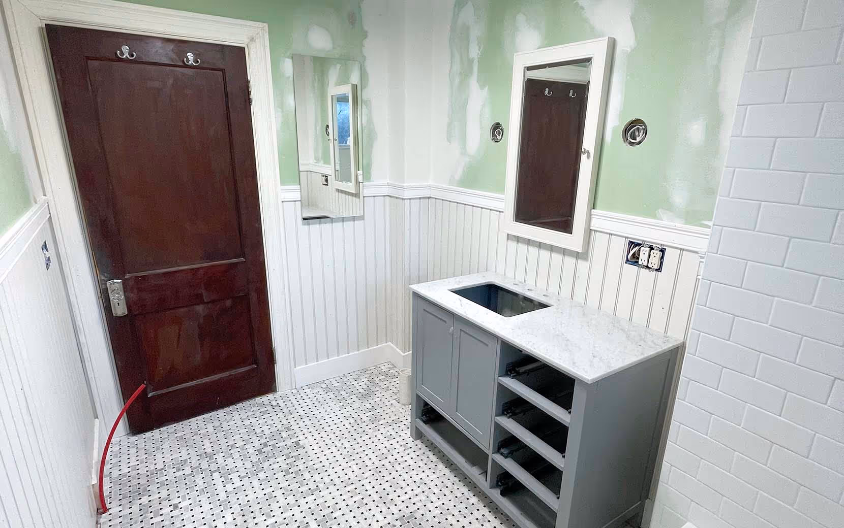Finalized view of renovated bathroom with vanity, mirror and door