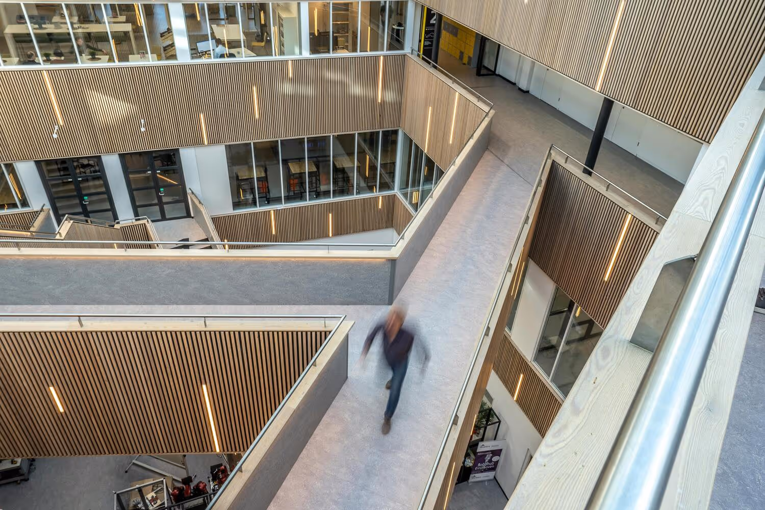 A slightly blurred image of a professional moving inside company office building through bridge and corridor