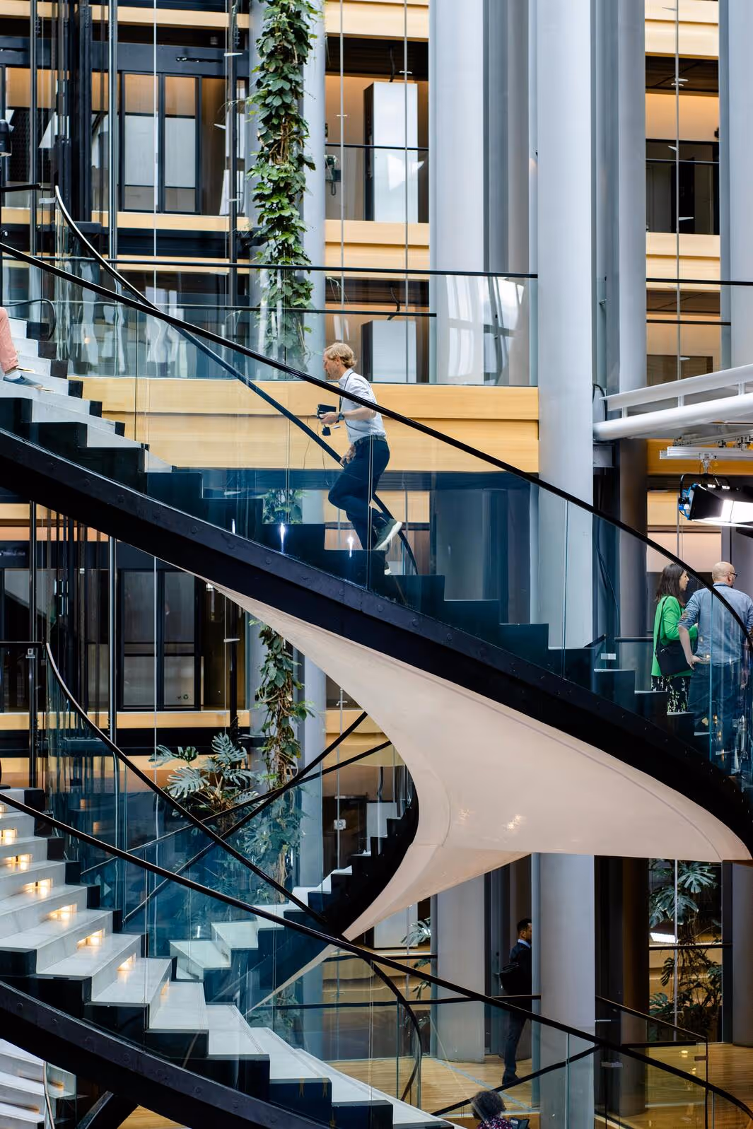 Modern spiral staircase inside a building with people walking up and down.