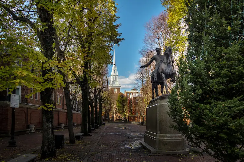 a statue of Paul Revere in the foreground of a historic Massachusetts street with an old church in the background