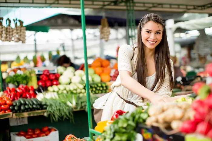 a cheerful woman works at a farmer's market stand