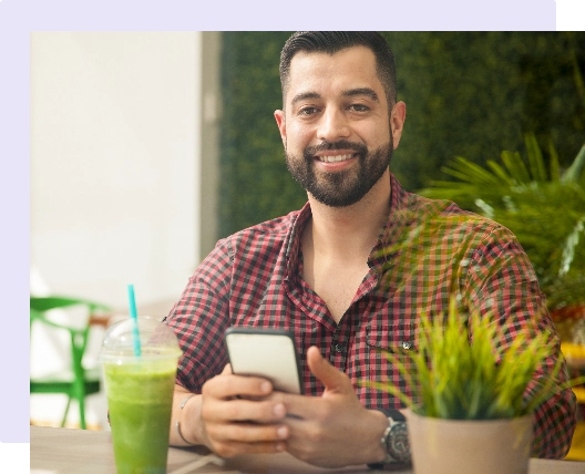 man working on his phone with a green smoothie