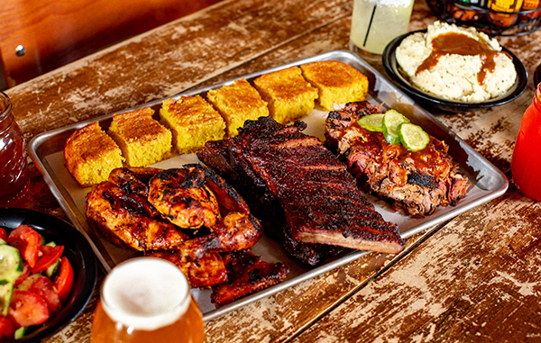 Photo of a tray of bbq meats and cornbread from Dinosaur BBQ