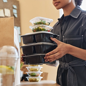 Woman placing delivery boxed lunches on a table