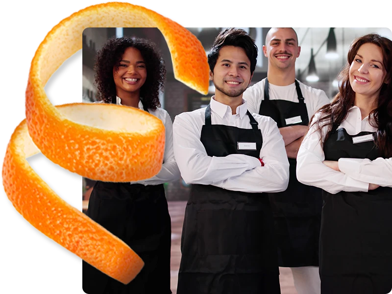 Four smiling food service workers wearing black aprons with arms crossed and an orange peel spiral.