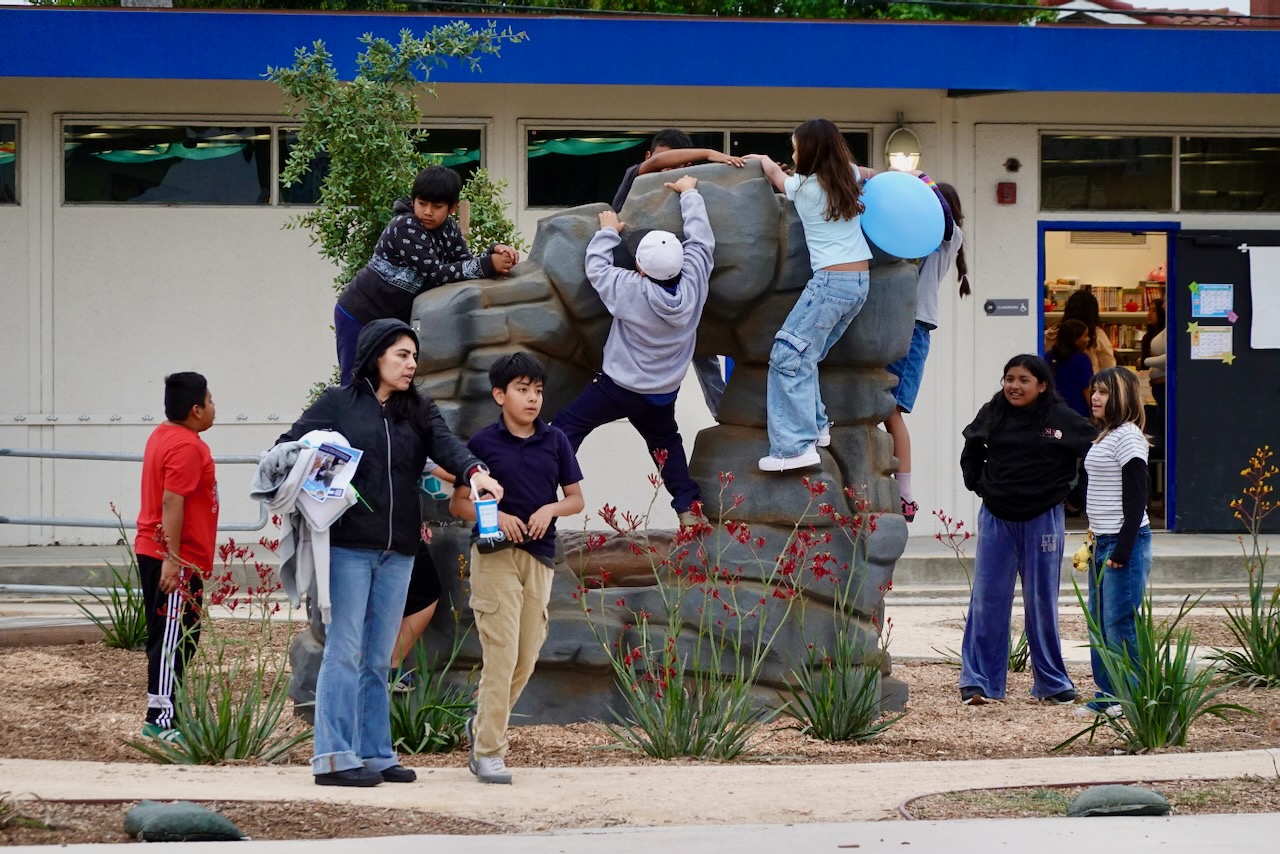 Students gather on the grass, enjoying a living schoolyard at an El Monte elementary school.