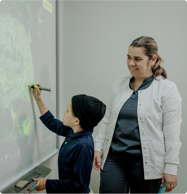 Niño con autismo escribiendo en la pizarra en sesión de Homeschooling en Developing Brains