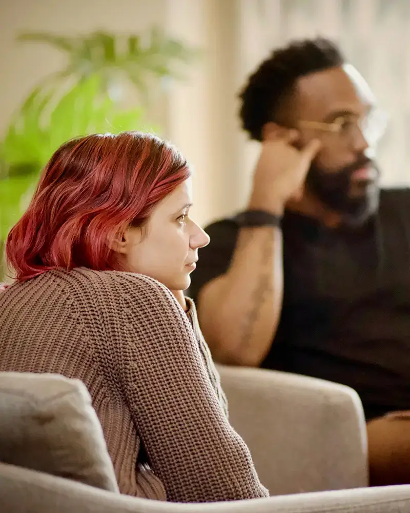 Two people listen intently to someone not pictured who must be talking. They both look contemplative and focused.