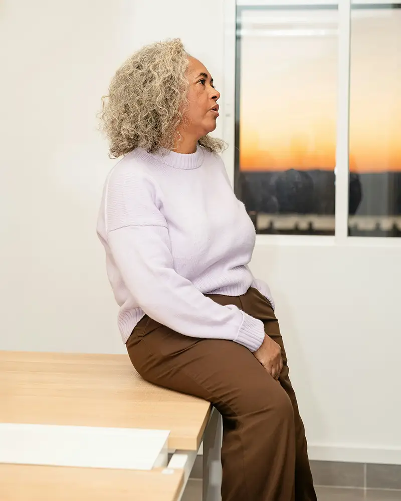 A woman sits on a table looking frustrated, or just simply over it