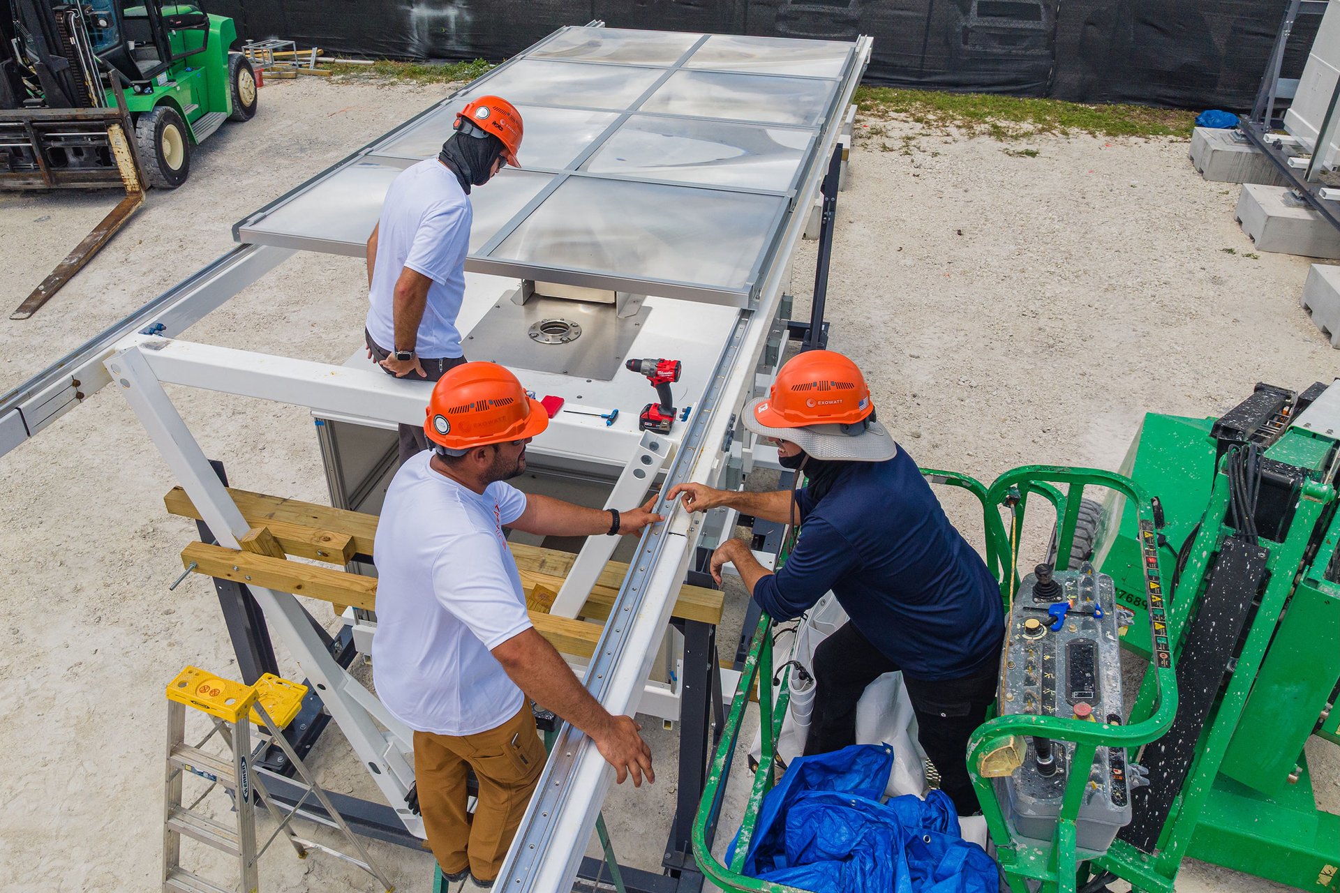 Exowatt team members in hard hats assembling a P3 unit outdoors