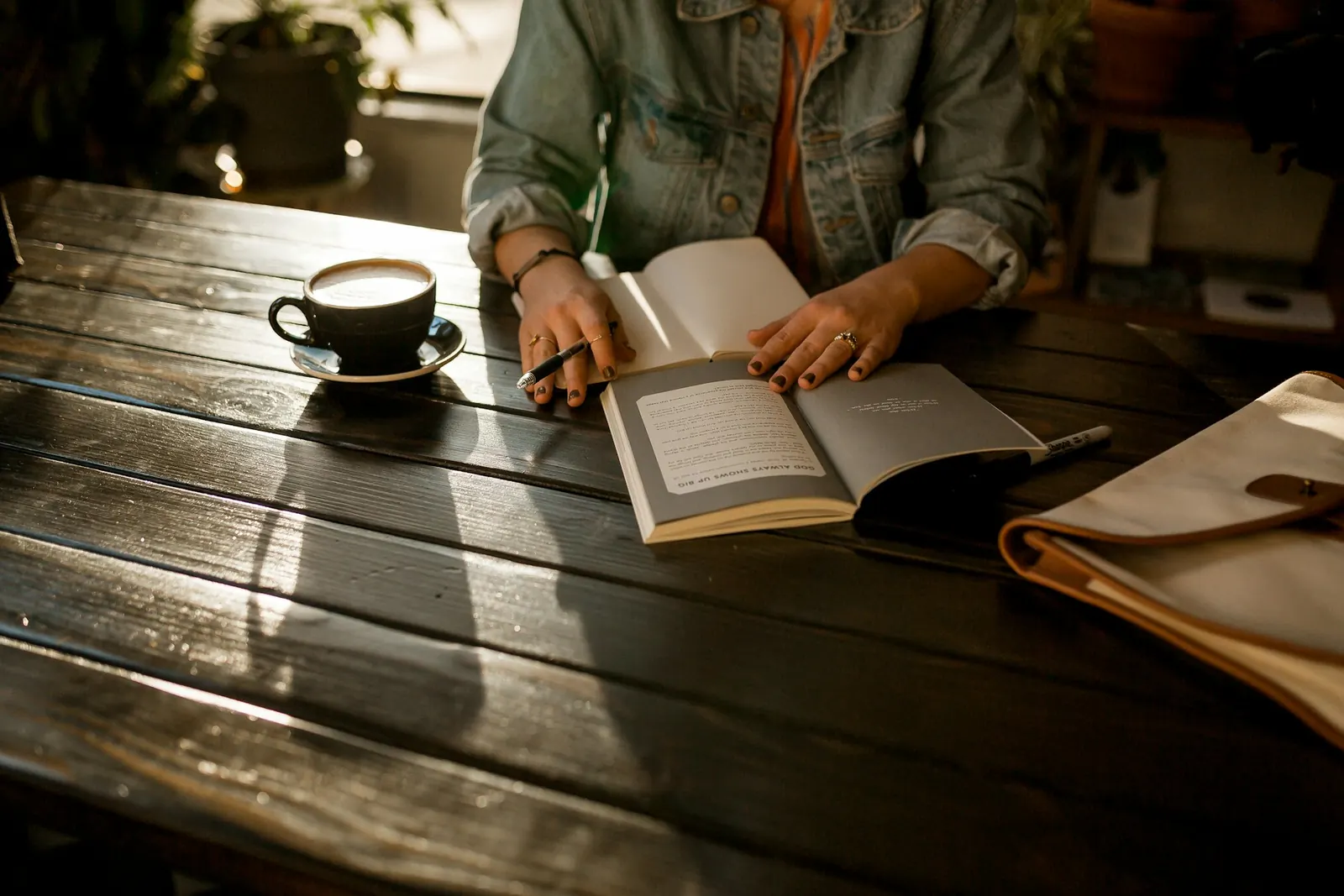 Person reading at a wooden table with coffee