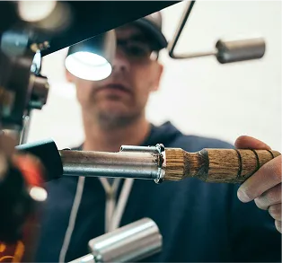 Worker using metal tool with wooden handle in industrial workshop
