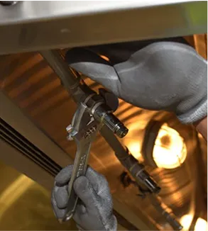 Gloved hand using spray gun under warm workshop lighting