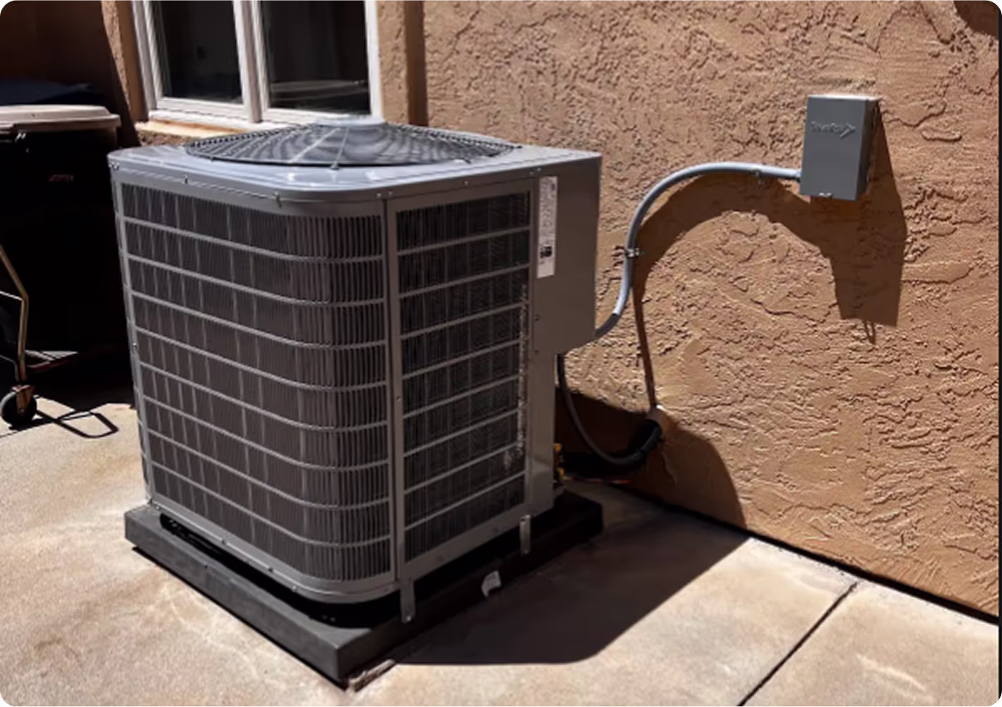 Air conditioning unit outside house on concrete pad near stucco wall