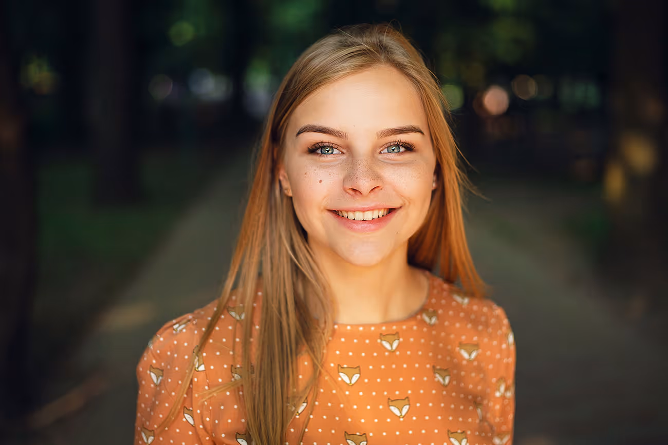 Smiling person in orange polka dot shirt with fox print outdoors