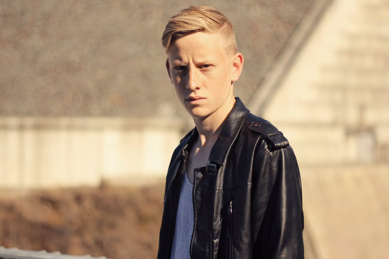 Young man with blonde hair and black leather jacket.