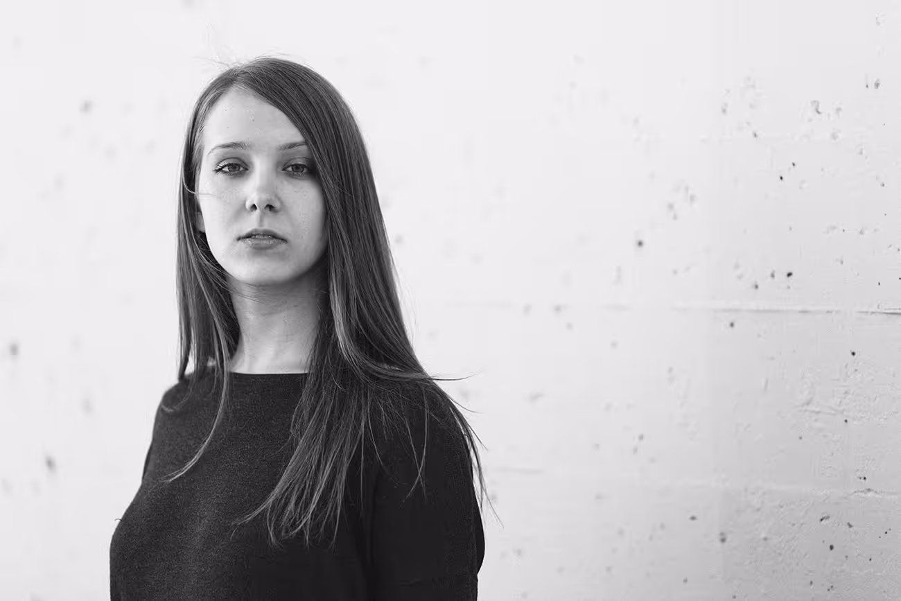 Black and white portrait of a woman with long hair against textured wall