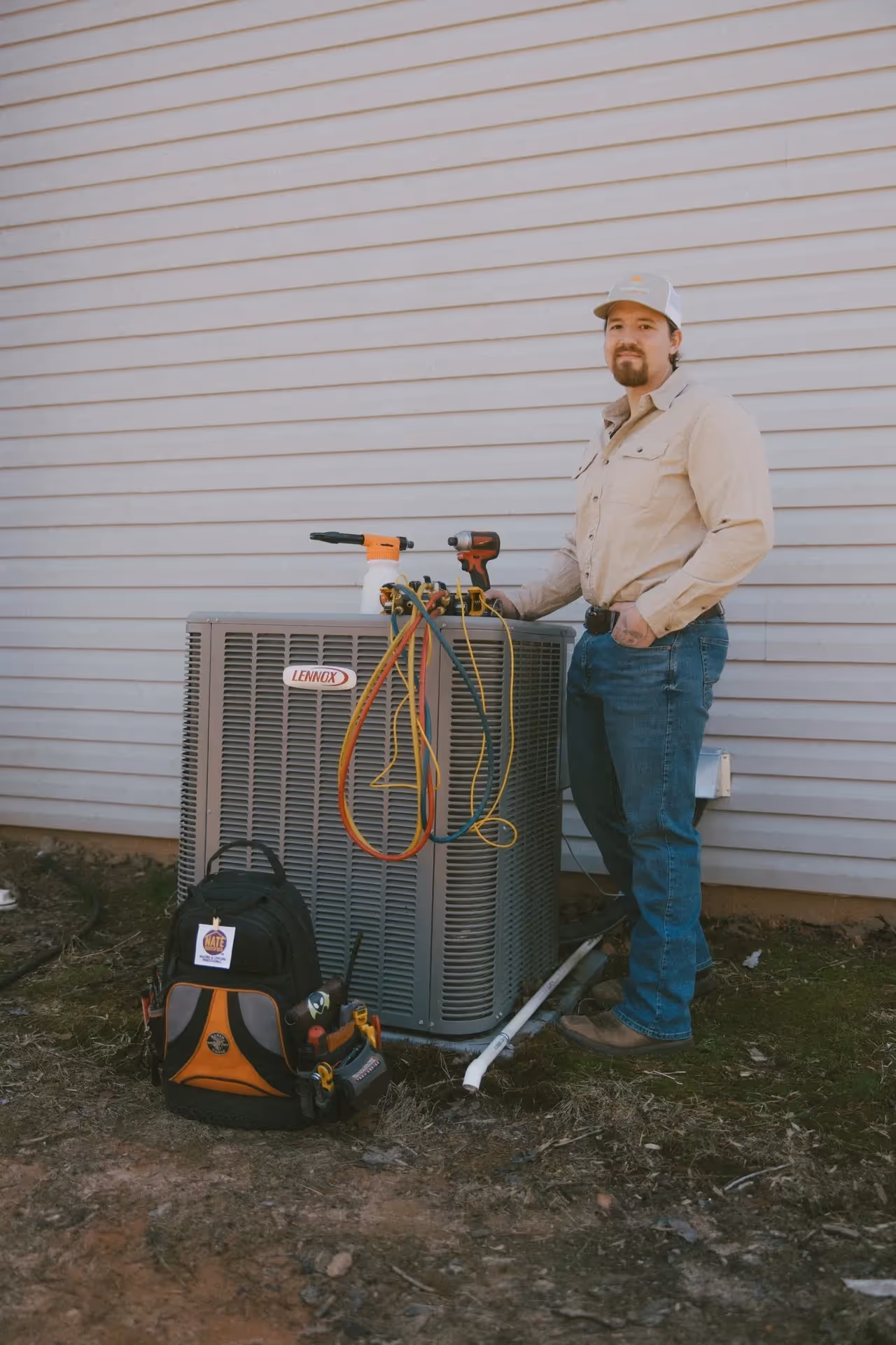 HVAC technician servicing Lennox air conditioning unit with tools.