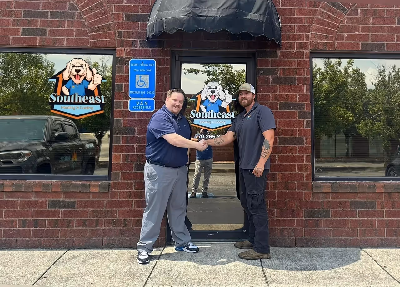 Two employees shaking hands outside Southeast Heating & Cooling office.