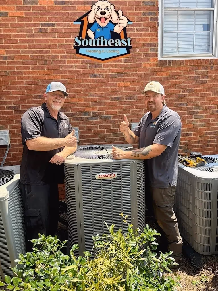 Two technicians giving thumbs up by Southeast Heating & Cooling HVAC unit.