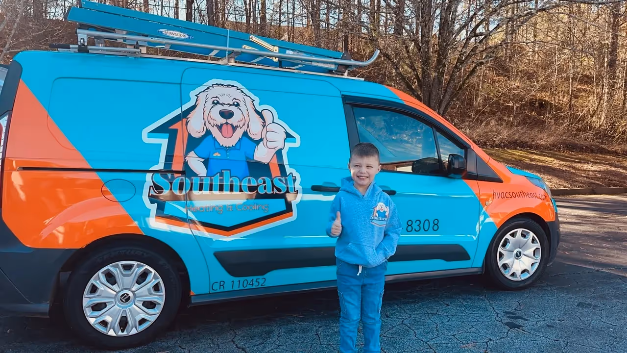 Blue and orange Southeast HVAC van with cartoon dog mascot and child.