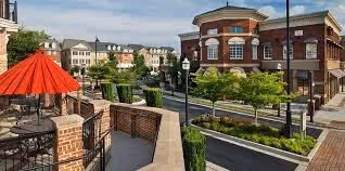 Urban park with red umbrella, brick buildings, and landscaped walkway.