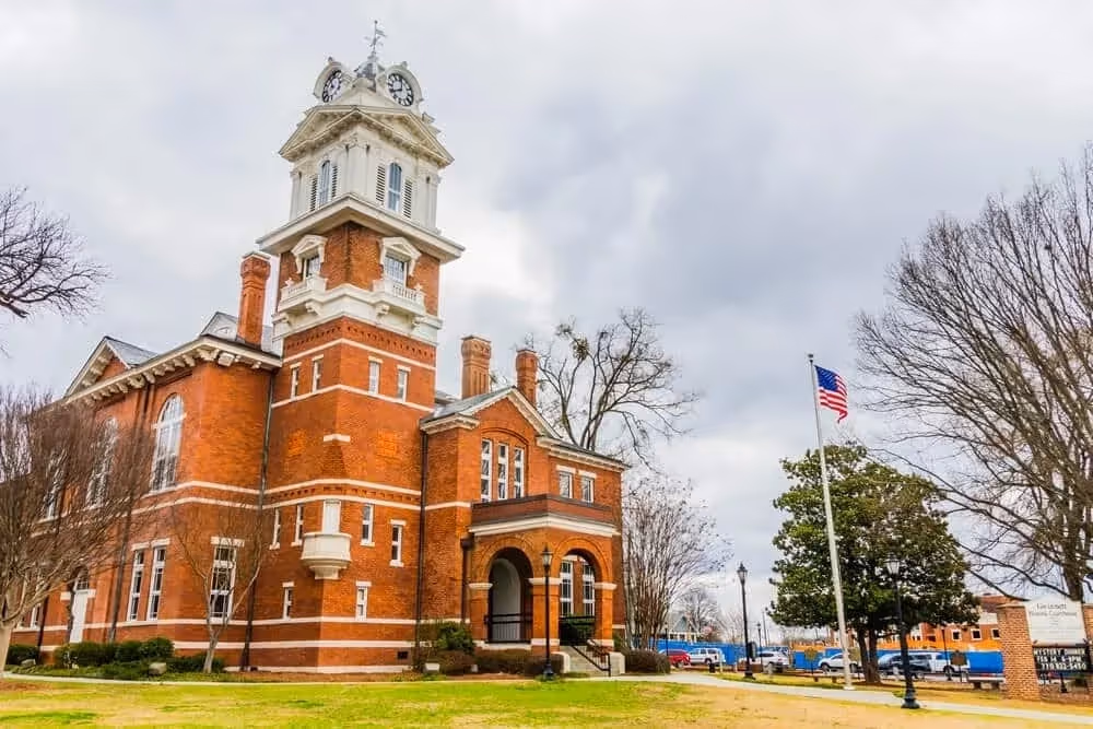 Historic red brick courthouse with clock tower and American flag.