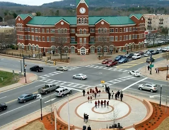 Large brick municipal building with clock tower at busy intersection
