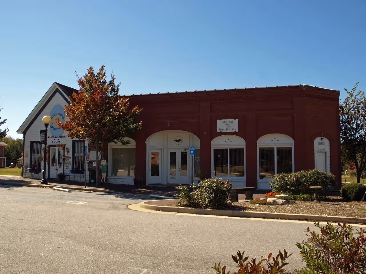 Historic brick and white buildings on small town street with autumn tree