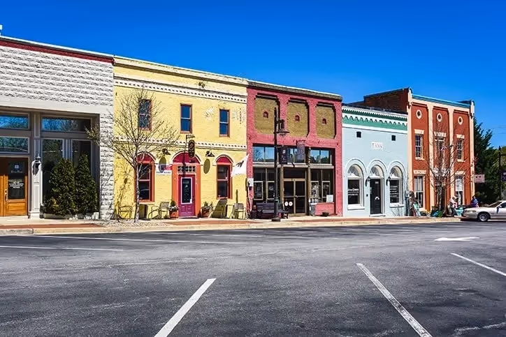 Colorful historic downtown storefronts with parking lot on sunny day