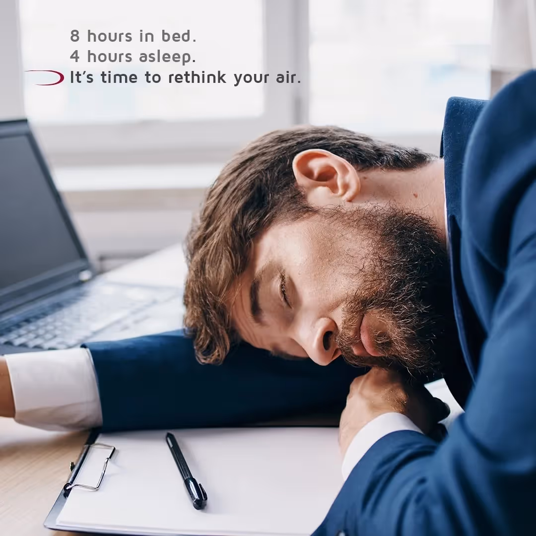 Exhausted person sleeping at desk with laptop and clipboard nearby