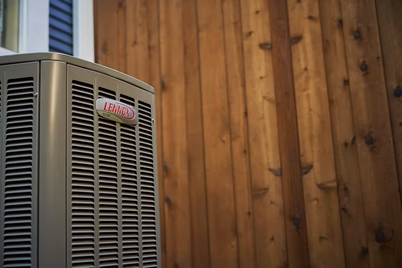 Lennox air conditioning unit mounted on wooden wall exterior